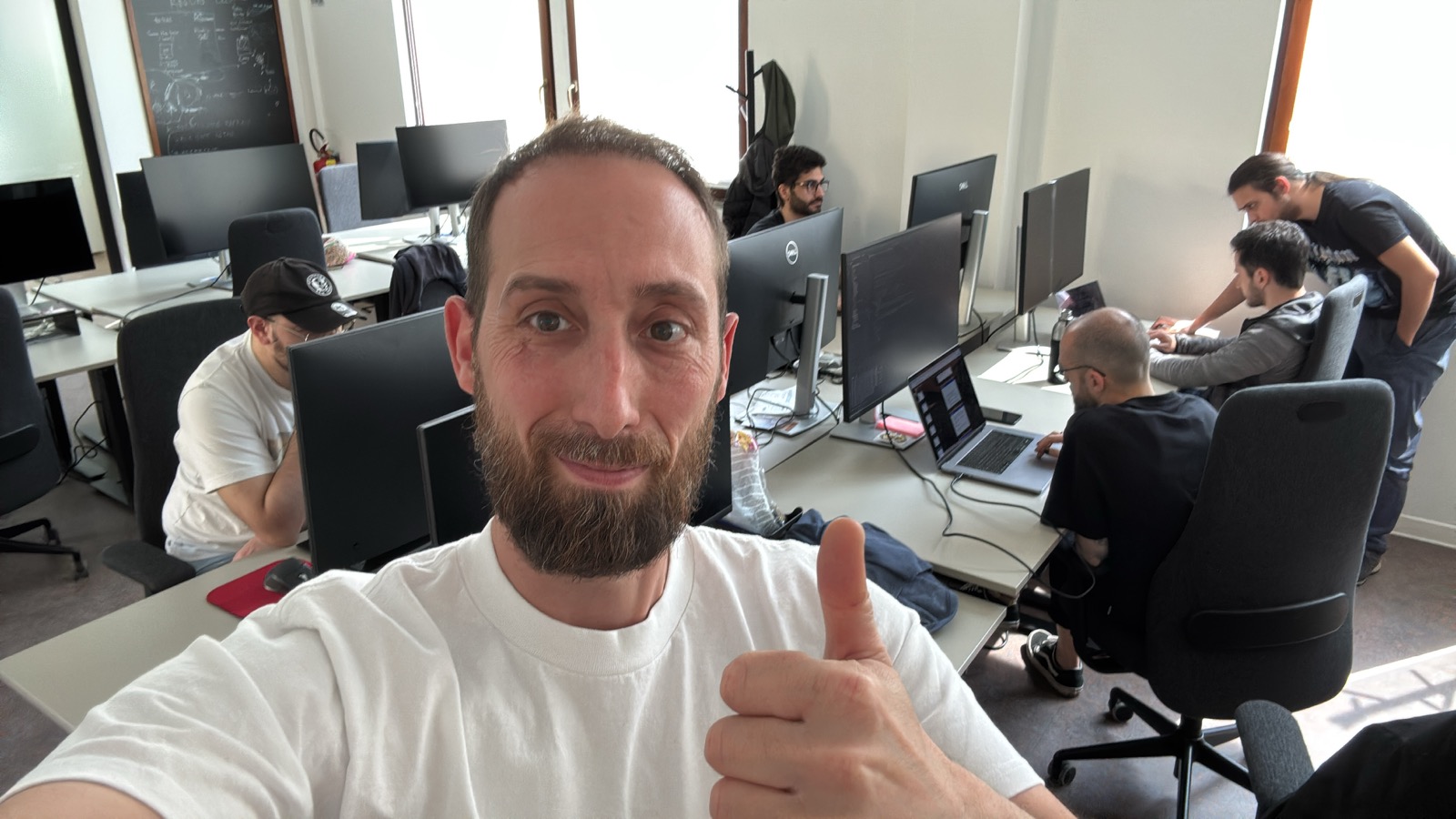 selfie of Francesco with a thumbs up, group of attendees in the background