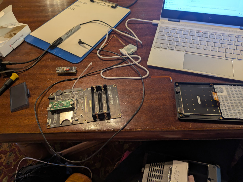 mess of cables, circuit boards, and tools on a wooden table
